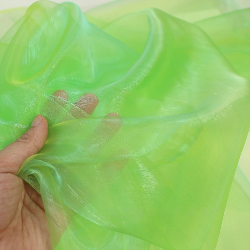A hand displays Longan Craft's Gradient Organza Fabric By The Yard, showing off the soft, lightweight ombre organza cloth’s translucent neon green texture.