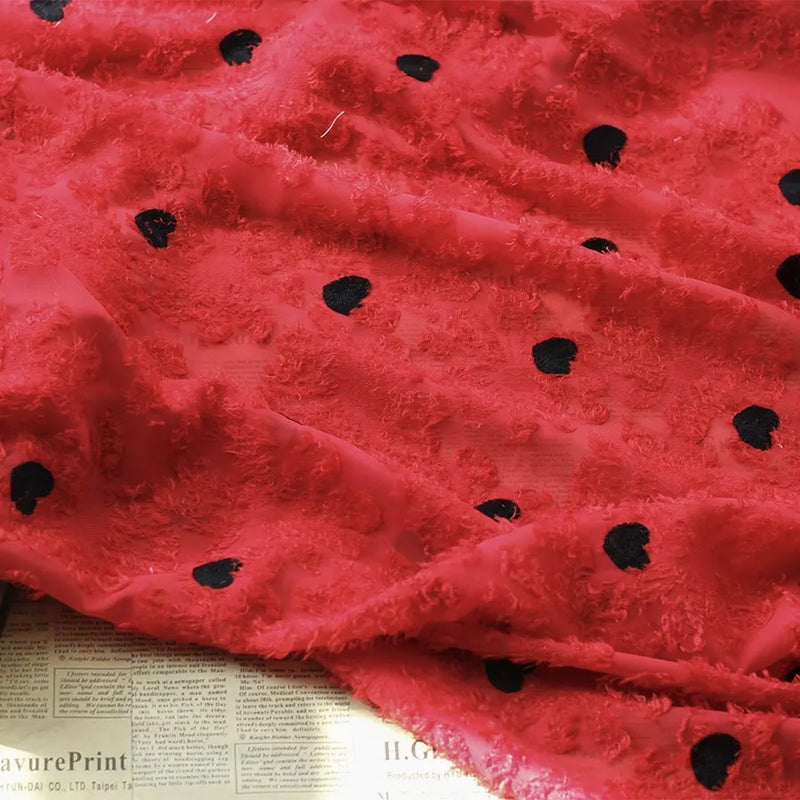 A piece of Heart Embroidered Tassel Chiffon Fabric by Longan craft is spread over a newspaper, sunlight softly highlighting the jacquard embroidered texture—perfect sewing material for spring and summer women’s dresses.