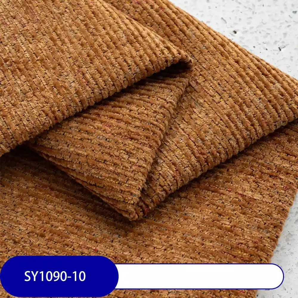 Folded pieces of textured brown Heavy Weight Slub Chenille Fabric by Longan Craft are stacked on a speckled surface. A blue and white label reads SY1090-10. This thick premium polyester fabric adds depth and style to any décor.