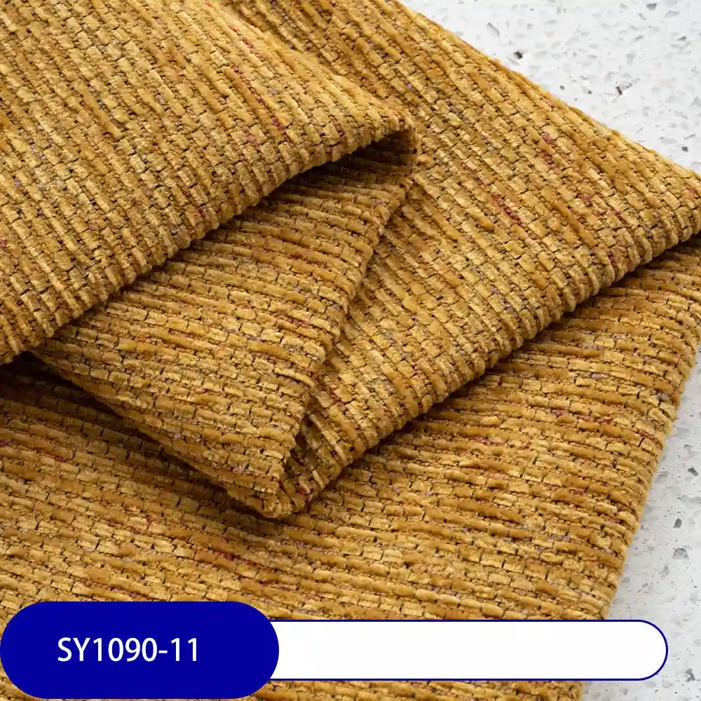 A close-up of folded, textured mustard yellow Heavy Weight Slub Chenille Fabric by Longan Craft, featuring a ribbed pattern on a light speckled surface. A label at the bottom left reads SY1090-11.