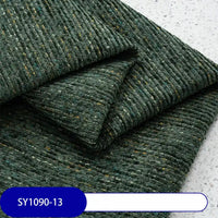 Folded dark green Heavy Weight Slub Chenille Fabric by Longan Craft, with yellow and blue flecks, sits on a light speckled surface. A blue label shows SY1090-13. Premium thick polyester chenille adds multicolor style to any upholstery project.