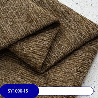 Close-up of Heavy Weight Slub Chenille Fabric By The Yard from Longan Craft, featuring thick brown ribbed polyester chenille upholstery material (SY1090-15), folded on a speckled surface with a blue and white label.