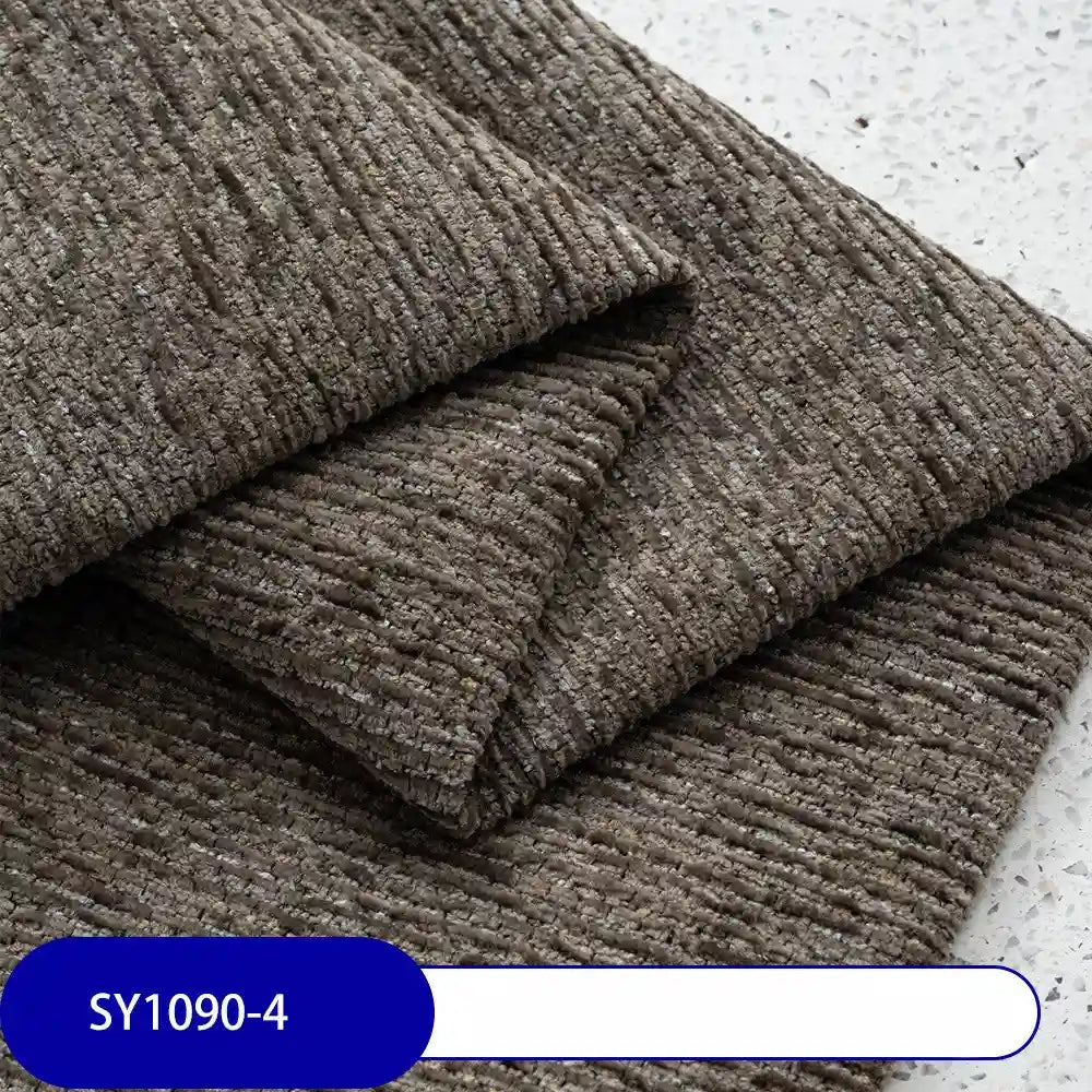 Three pieces of Heavy Weight Slub Chenille Fabric by Longan Craft, in a ribbed brownish-gray pattern, are stacked on a speckled surface. The label reads SY1090-4, highlighting this premium polyester chenille upholstery material.