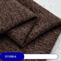 A close-up of Heavy Weight Slub Chenille Fabric By The Yard from Longan Craft shows folded, ribbed brown upholstery with yellow and red flecks on a light speckled surface and a blue label reading SY1090-6 at the bottom.