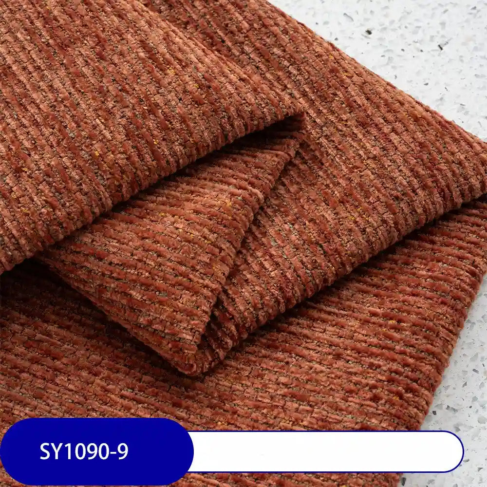 A close-up shows premium Heavy Weight Slub Chenille Upholstery Fabric by Longan Craft in reddish-brown, neatly folded on a light speckled surface. A SY1090-9 label appears in white text on a blue background at the bottom.