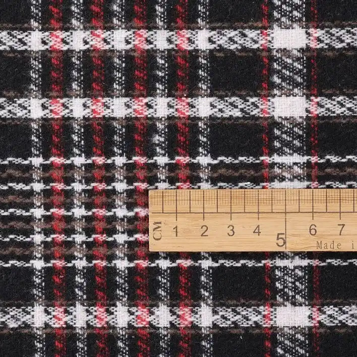 A Longan Craft Heavyweight Cotton Checked Flannel Fabric By The Yard—Polyester Brushed Mammoth Flannel Clothing Material—is shown beneath a wooden ruler spanning approximately 8 cm, measuring the width of its black, white, and red checked pattern. This vintage fall winter flannel textile is ideal for cozy seasonal sewing projects.