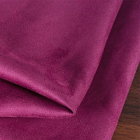 A close-up shows folded, smooth magenta Heavyweight Microfiber Faux Suede Fabric By The Yard from Longan Craft, featuring a slight sheen and resting on a wooden surface.