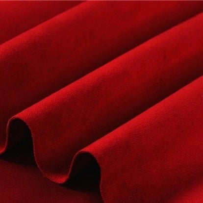 Close-up of rich red velvet fabric with soft folds and a smooth, plush texture, beautifully highlighting its luxurious material and deep, vibrant hue—an ideal complement to Longan Craft’s Heavyweight Microfiber Faux Suede Fabric By The Yard, a multicolor brushed microsuede material perfect for sophisticated upholstery or pairing in DIY clothing projects.