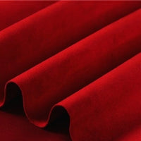 Close-up of rich red velvet fabric with soft folds and a smooth, plush texture, beautifully highlighting its luxurious material and deep, vibrant hue—an ideal complement to Longan Craft’s Heavyweight Microfiber Faux Suede Fabric By The Yard, a multicolor brushed microsuede material perfect for sophisticated upholstery or pairing in DIY clothing projects.