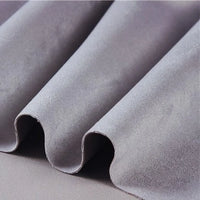 Close-up of heavyweight microfiber faux suede fabric by the yard from Longan Craft in light gray, featuring gentle, soft folds that showcase its smooth and plush texture—resembling the luxurious feel of multicolor brushed microsuede material.