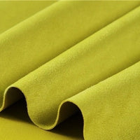 Close-up of the Heavyweight Microfiber Faux Suede Fabric By The Yard from Longan Craft in a vibrant yellow-green shade, beautifully arranged in soft, even folds. The smooth and plush brushed microsuede texture highlights its luxurious feel and rich color—making it an ideal choice for upholstery or DIY clothing projects requiring high-quality imitation suede.