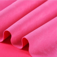 Close-up of folded bright pink Heavyweight Microfiber Faux Suede Fabric By The Yard from Longan Craft, featuring a smooth and soft texture with gentle waves and shadows that accentuate its vibrant color and even surface—a premium multicolor brushed microsuede material, perfect for DIY clothing projects or upholstery.