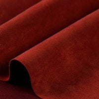 A close-up of rich, reddish-brown velvet fabric showcases soft folds and a plush, smooth texture—evoking the luxurious feel of Longan Craft Heavyweight Microfiber Faux Suede Fabric by the Yard. This multicolor brushed microsuede material is prized both for its inviting softness and its elegant imitation suede appearance, making it ideal for upholstery or DIY clothing projects.
