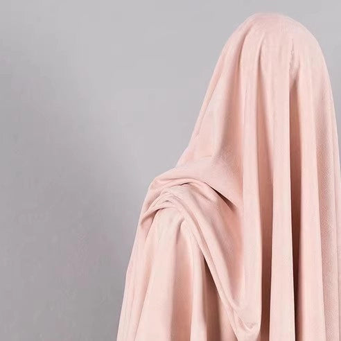 A person is fully draped in Longan Craft’s Heavyweight Microfiber Faux Suede Fabric—a soft, pale pink imitation suede ideal for DIY clothing projects—concealing their face and body against a plain gray background.