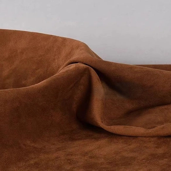 A close-up of Longan Craft’s Heavyweight Microfiber Faux Suede Fabric By The Yard, featuring soft multicolor brushed microsuede material draped in gentle folds against a plain light background.