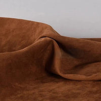 A close-up of Longan Craft’s Heavyweight Microfiber Faux Suede Fabric By The Yard, featuring soft multicolor brushed microsuede material draped in gentle folds against a plain light background.