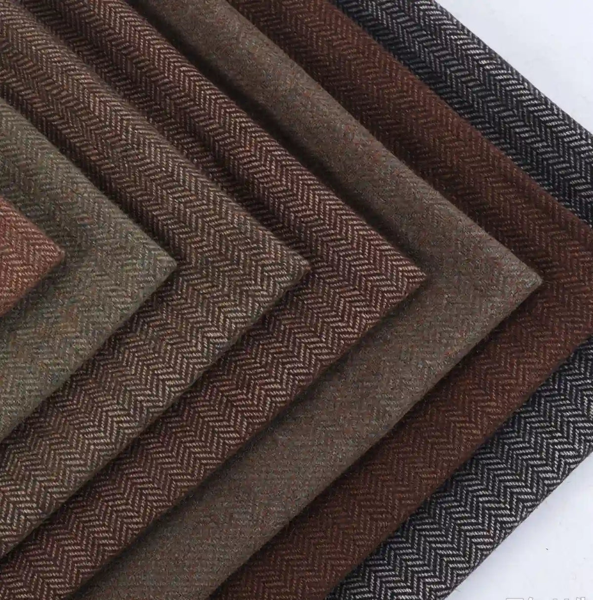 Stacked swatches of Herringbone Wool Fabric By The Yard in various shades of brown and gray.