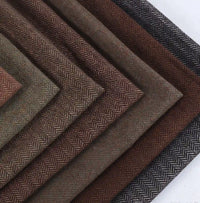 Stacked swatches of Herringbone Wool Fabric By The Yard in various shades of brown and gray.
