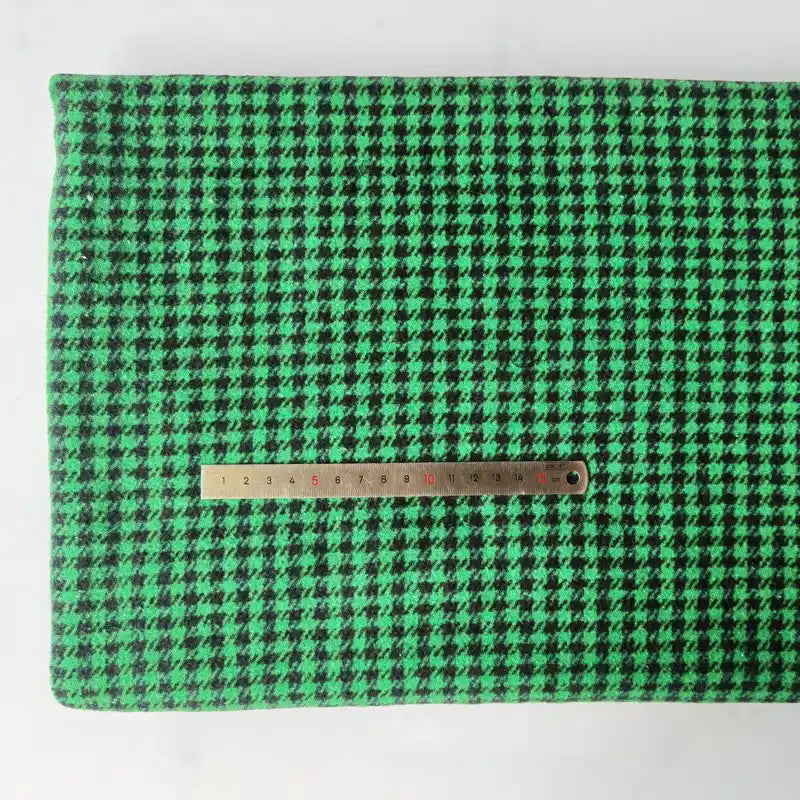 The Longan Craft Houndstooth Mammoth Flannel Fabric By The Yard is shown flat with a metal ruler for scale, highlighting the green and black brushed polyester cotton blend—perfect as a comfy fall flannel textile.
