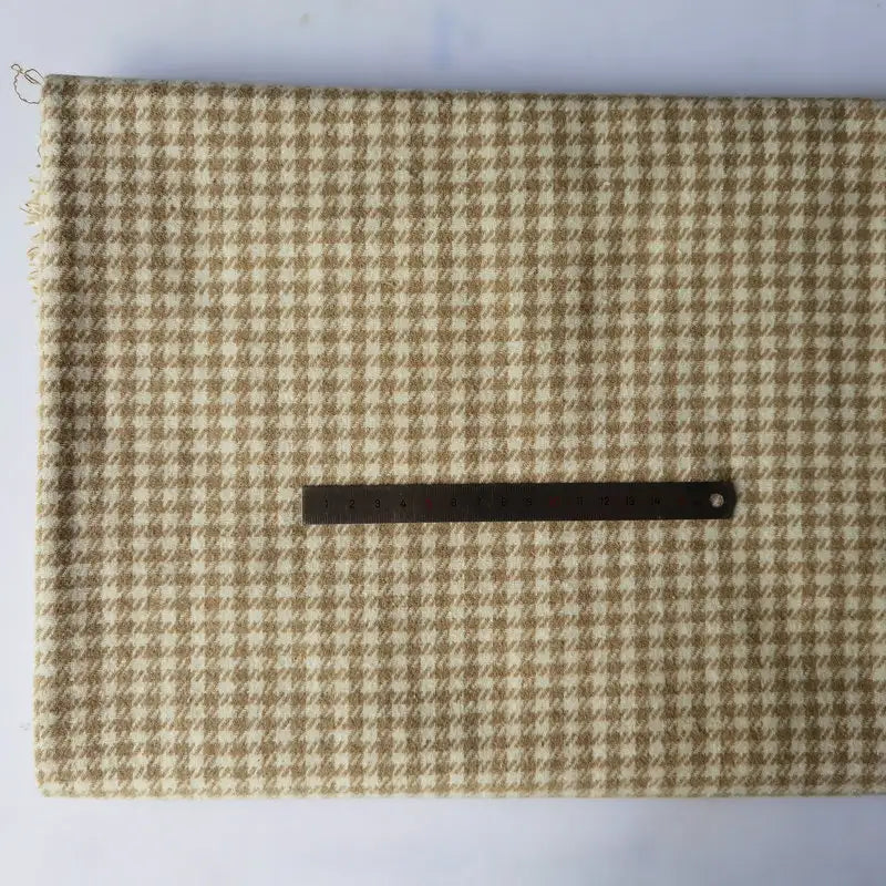 A piece of Longan Craft Houndstooth Mammoth Flannel Fabric (beige/white, brushed polyester-cotton) is laid flat with a black ruler on top for scale. This comfy fall flannelette is available by the yard.