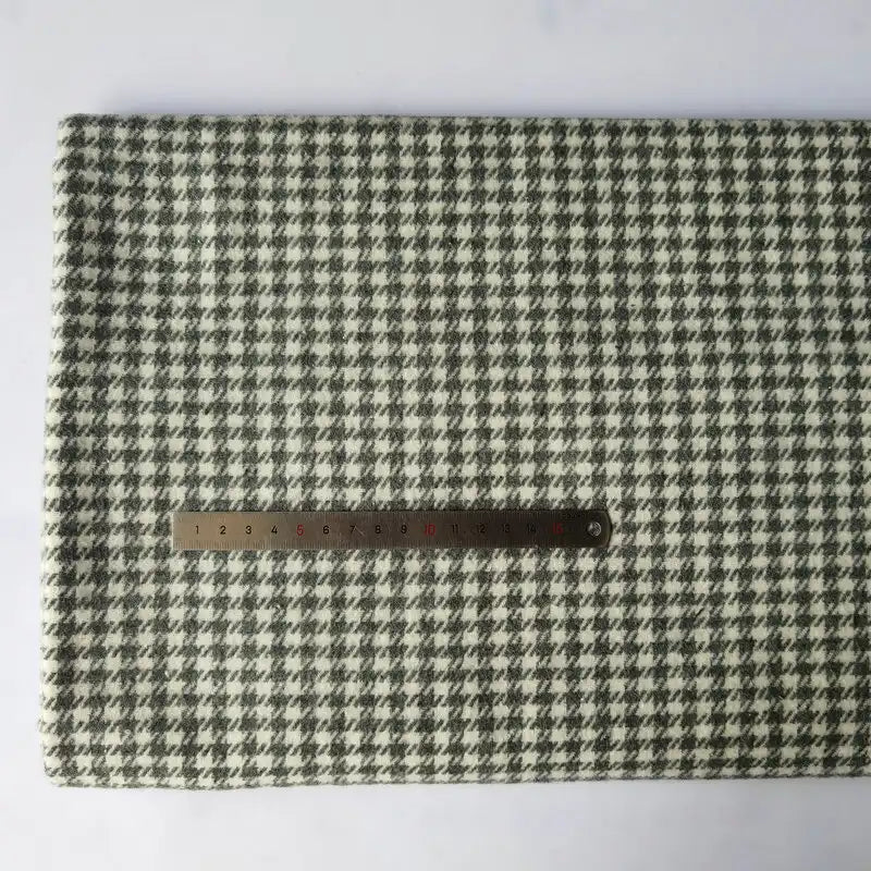 The Longan Craft Houndstooth Mammoth Flannel Fabric by the yard, a comfy black and white brushed polyester cotton flannelette, is laid flat on a white surface with a metal ruler across it for scale.