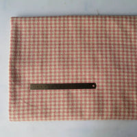A piece of Longan Craft Houndstooth Mammoth Flannel Fabric in pink and cream rests folded on a white surface, with a metal ruler on top for scale. This brushed polyester cotton flannelette is sold by the yard, perfect for cozy fall projects.