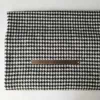 A piece of Longan Craft Houndstooth Mammoth Flannel Fabric by the yard is laid flat with a metal ruler on top, displaying the scale of its black and white pattern on a plain white background.