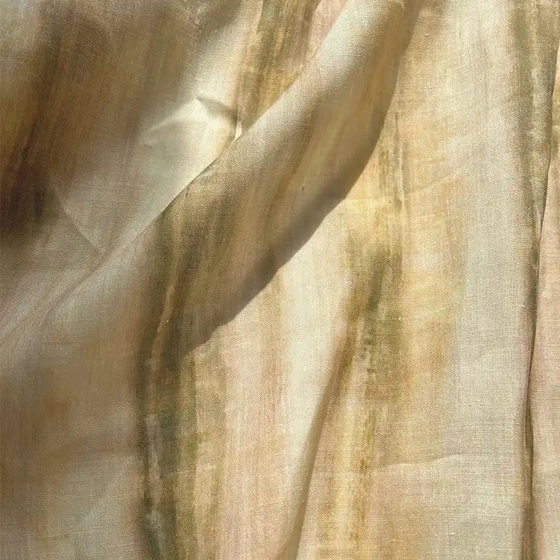 Sunlight filters through Longan Craft’s Irregular Stripe Printed Ramie Fabric—a sheer, breathable, and lightweight striped material in soft green and tan—casting gentle shadows and creating a natural, airy texture that’s perfect for dressmaking.