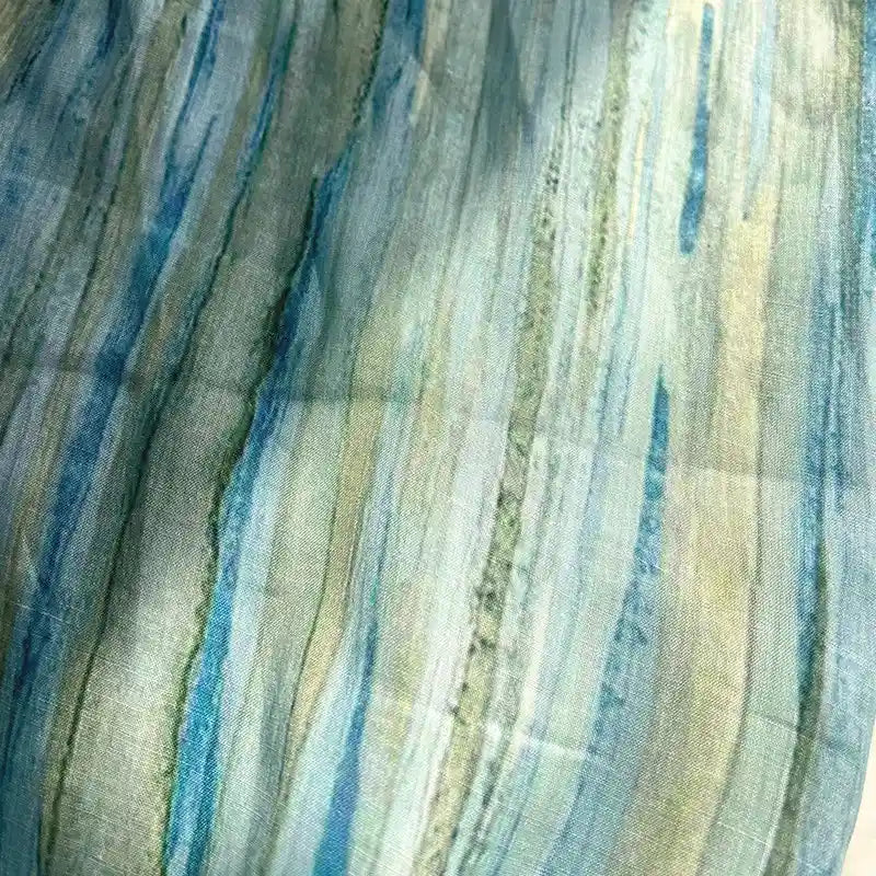Introducing the Irregular Stripe Printed Ramie Fabric By The Yard by Longan Craft—a close-up showcases its lightweight, sheer texture with vertical, watercolor-like stripes in blue, green, and beige. This breathable ramie material features a soft, flowing pattern of irregular stripes, making it the ideal choice for airy and elegant dressmaking projects.