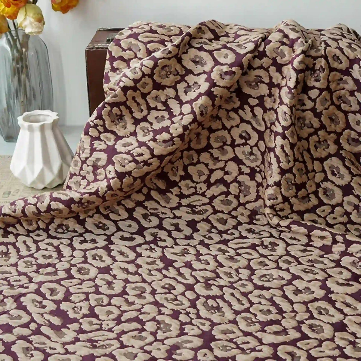 Leopard Embossed Brocade Fabric by Longan Craft, a vintage stretch jacquard brocade for dressmaking, displayed with a white geometric vase and flowers in the background.