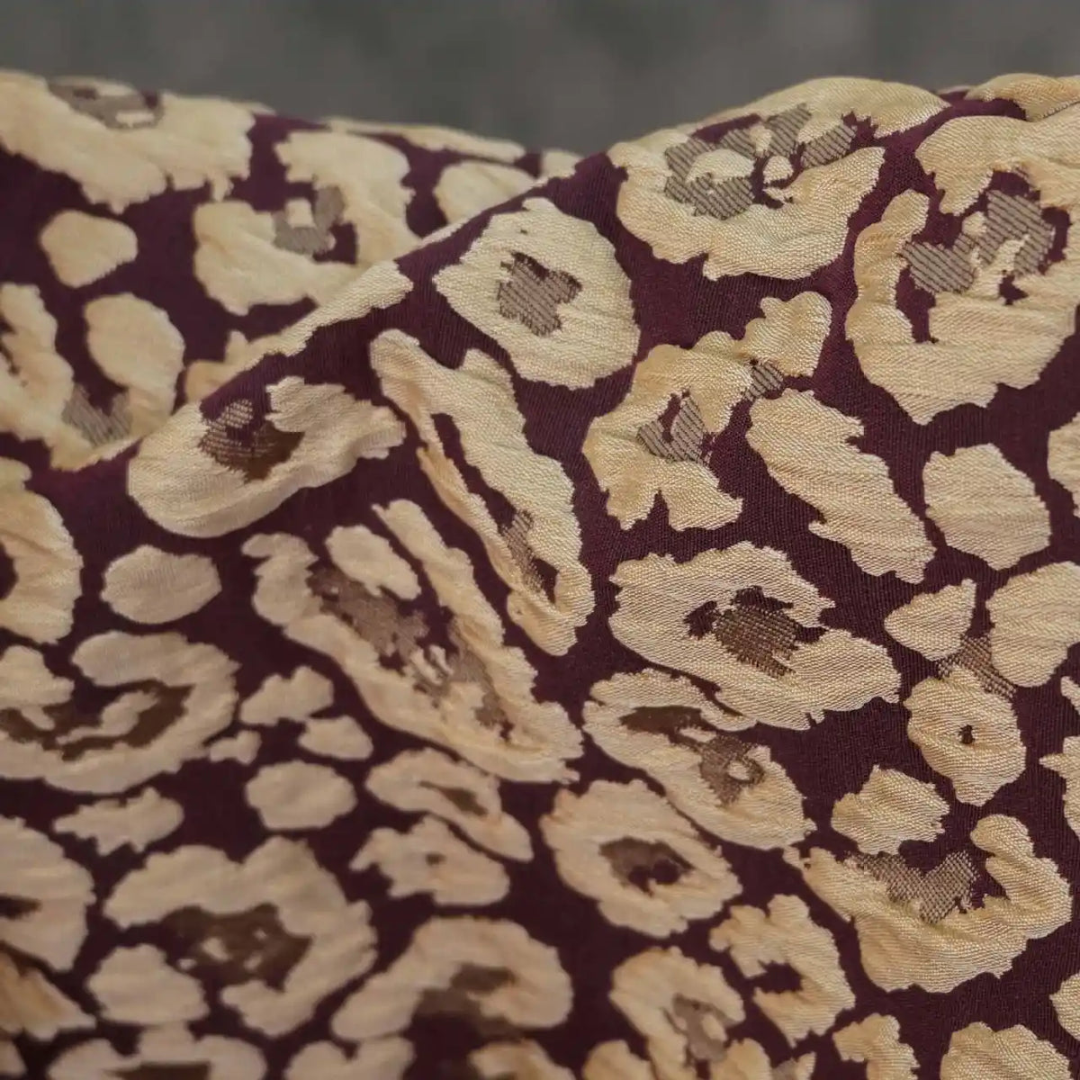 Close-up of Longan Craft's Leopard Embossed Brocade Fabric by the yard, a stretch jacquard with vintage leopard pattern on dark maroon—ideal textured material for dressmaking.