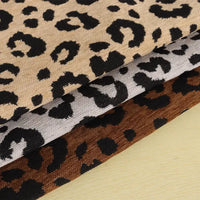 Three folded swatches of Leopard Jacquard Chenille Fabric By The Yard in tan, gray, and brown.