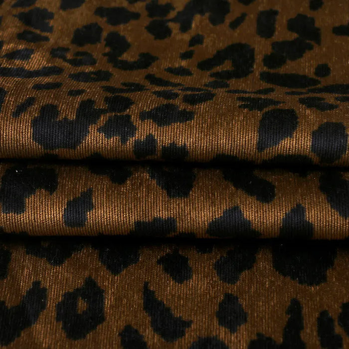 A close-up of Longan Craft's Leopard Print Corduroy Fabric by the yard shows soft, slightly shiny multicolor material with bold black spots—ideal for kids' clothing and fashion projects.