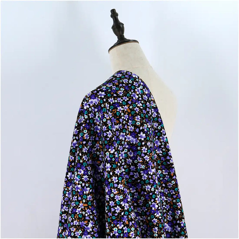 A mannequin displays the Longan Craft Lily Printed Cotton Corduroy Fabric, a fine wale cotton material with a dense floral print in purple, blue, white, and brown on white—perfect for comfy tops and available by the yard.