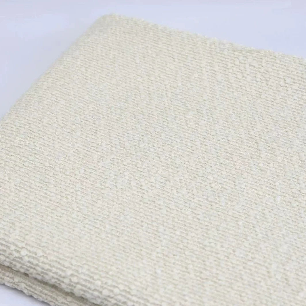 A folded piece of off-white, textured Linen Grain Boucle Fabric By The Yard.