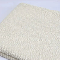 A folded piece of off-white, textured Linen Grain Boucle Fabric By The Yard.