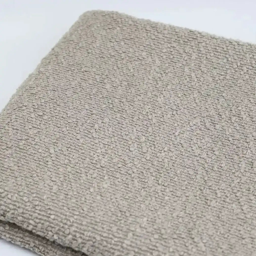 Folded square of beige Linen Grain Boucle Fabric with a distinctive linen grain texture.