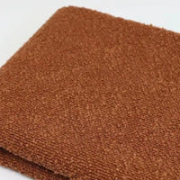 Folded piece of brown textured Linen Grain Boucle Fabric By The Yard with a prominent linen grain.