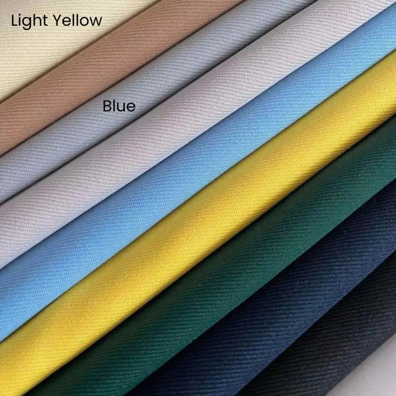 Nine diagonally stacked pieces of Longan Craft's Matte Finish Gabardine Fabric By The Yard show smooth, wrinkle-resistant pastel and dark shades, including labeled "Light Yellow" and "Blue," with a high-quality twill weave perfect for jackets.
