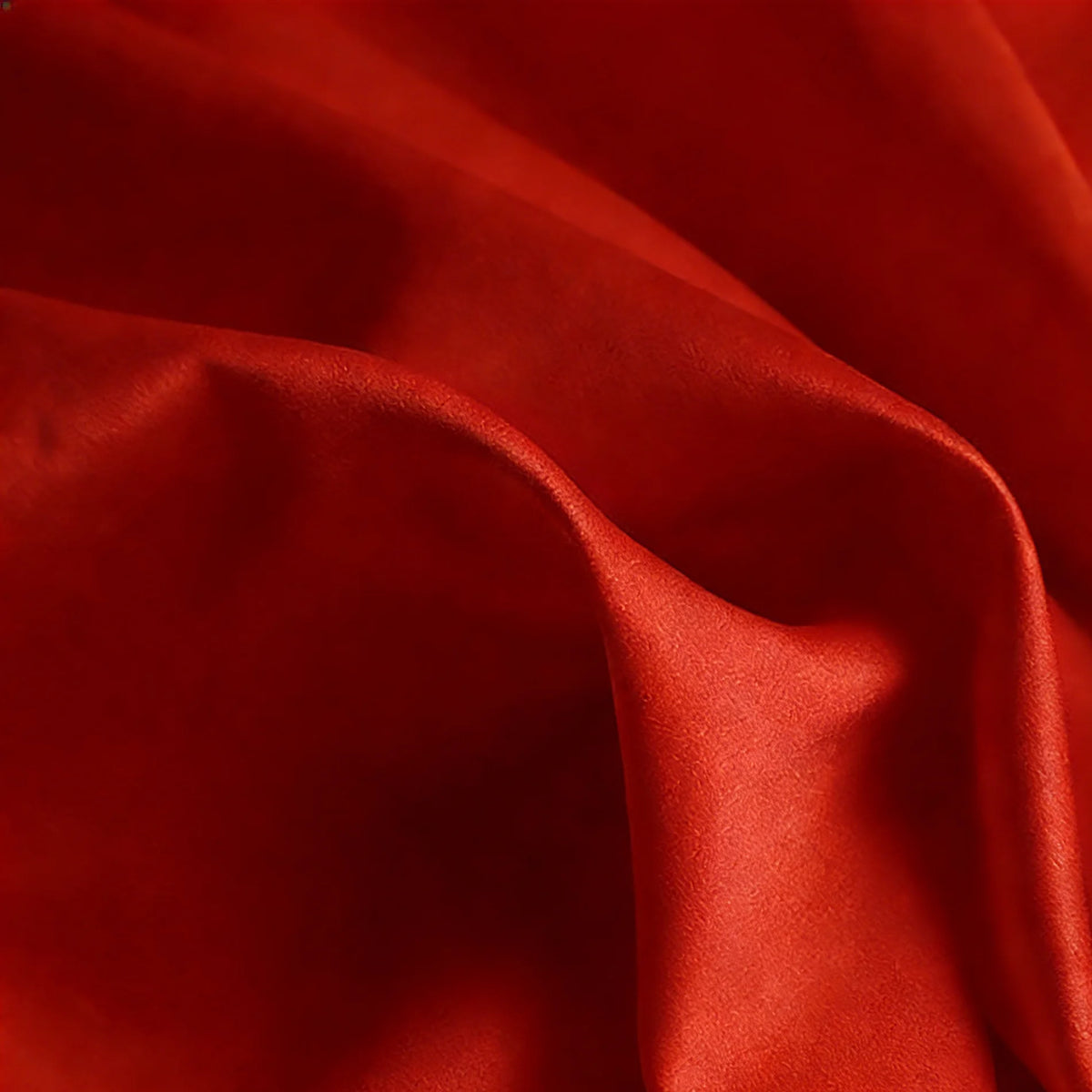 A close-up of Longan Craft’s Matte Satin Fabric By The Yard shows its vibrant red color, smooth texture, and gentle folds—ideal for solid color bridesmaid dresses and other comfortable garment projects.