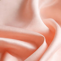 Longan Craft's Matte Satin Fabric By The Yard features a soft peach color with a matte finish and subtle sheen, offering smooth, flowing folds—perfect for elegant wedding dresses, bridesmaid apparel, and other luxurious garments.