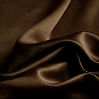 A close-up of Longan Craft's Matte Satin Fabric shows smooth, dark brown material with gentle folds and a subtle sheen—ideal for comfortable bridesmaid dresses and special occasion wear.