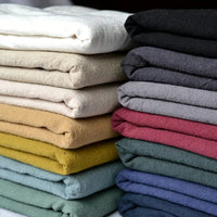 Neatly stacked Medium Weight Viscose Linen Fabric by Longan Craft, featuring a washed finish in colors like white, beige, mustard yellow, green, teal, and more—perfect breathable fabric for clothing and crafts.