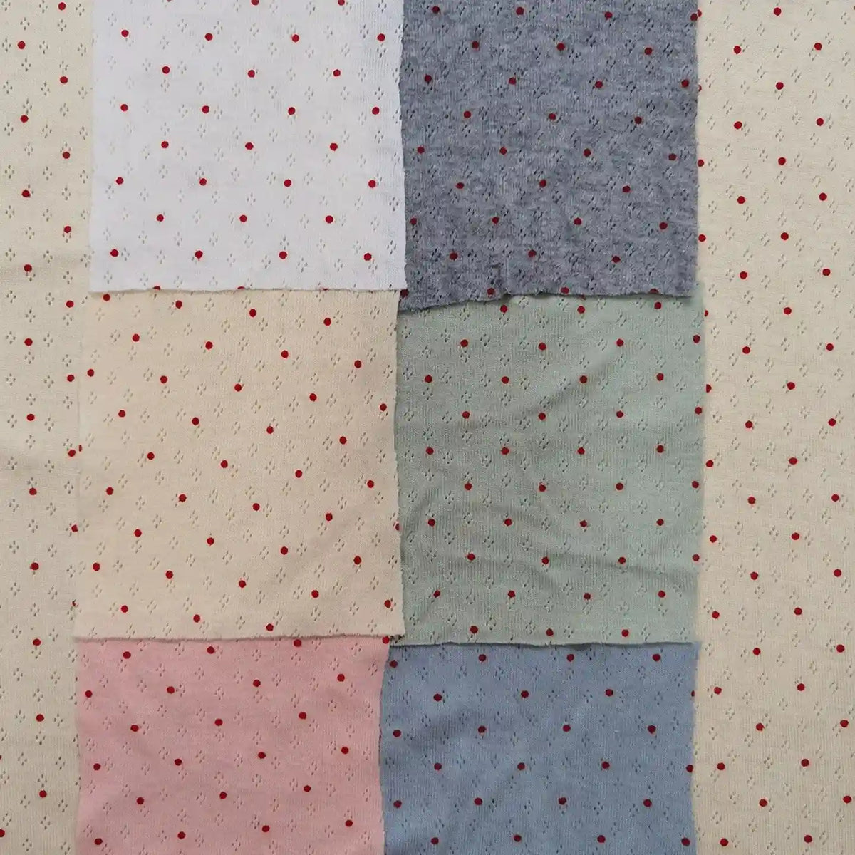 Six swatches of Mini Red Dot Printed Pointelle Fabric By The Yard in white, cream, pink, grey, green, and blue, arranged in a grid over a cream-colored red-dotted background.
