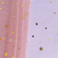 Moon Star Sequins Tulle Fabric by the yard from Longan Craft features multicolor glitter, pink mesh, and gold star confetti—perfect for stage costumes. Gold stars accent a white textured surface for a dazzling look.