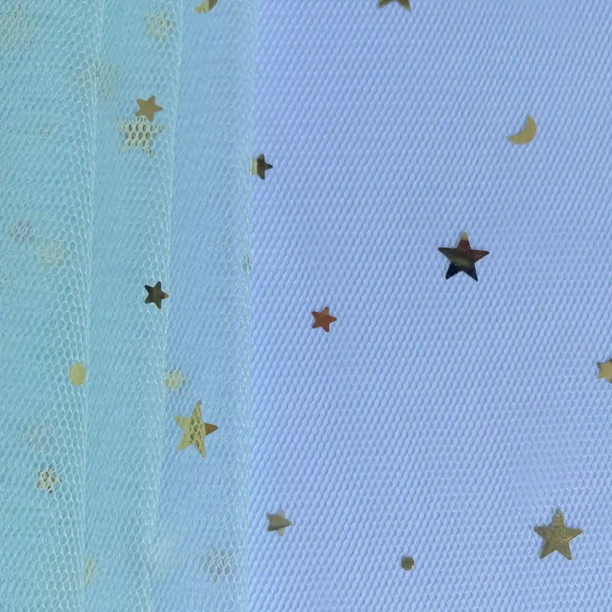 Close-up of Longan Craft's Moon Star Sequins Tulle Fabric by the yard in light blue, with gold star and moon confetti—ideal for stage costumes or dancewear. Background texture shows through this multicolor glitter tulle material.