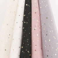 Five Moon Star Sequins Tulle Fabrics by Longan Craft in cream, white, black, pink, and lavender hang side by side. Each multicolor glitter tulle is ideal for stage costumes or elegant attire.