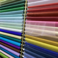 Rolls of Longan Craft Multicolor 8 Momme Organza Silk Fabric by the yard—luxury mulberry silk for dresses—are displayed by color: green, blue, and purple on the left; red, pink, yellow, and white gown-ready shades on the right.