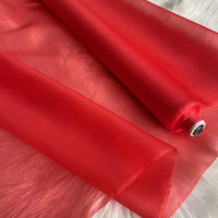 A partially unrolled yard of Longan Craft’s Multicolor 8 Momme Organza Silk Fabric—pure mulberry silk—rests on a white textured surface, highlighting its luxurious, sheer, and translucent quality for elegant dresses.