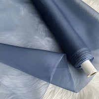 A roll of Longan Craft Multicolor 8 Momme Organza Silk Fabric By The Yard, made from pure Mulberry silk, is unrolled on a white surface, showcasing its delicate and translucent luxury—ideal for dreamy dresses.